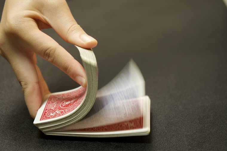 A deck of playing cards riffling between fingers, caught mid-motion