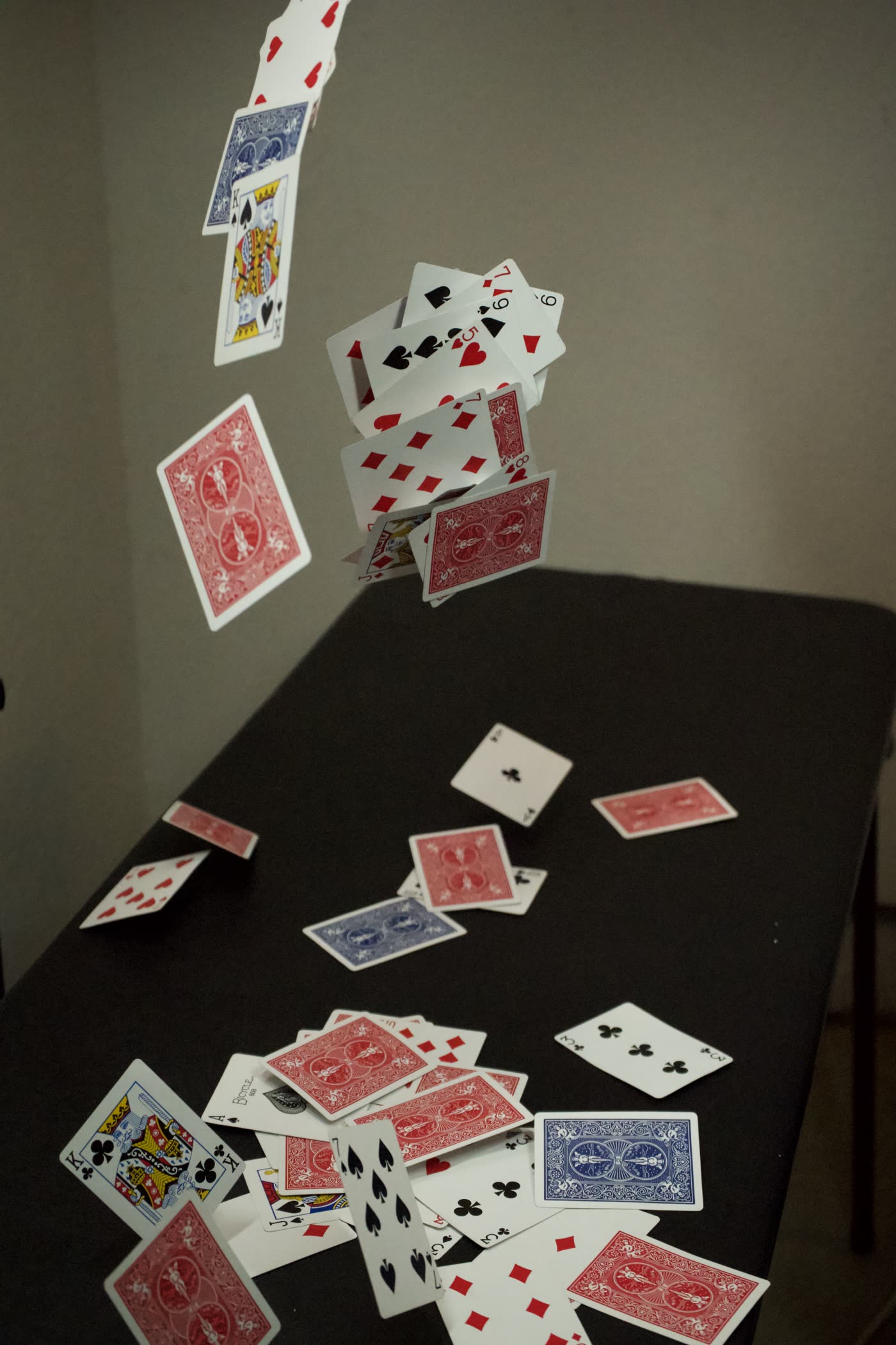 Playing cards scattering through the air above a dark table