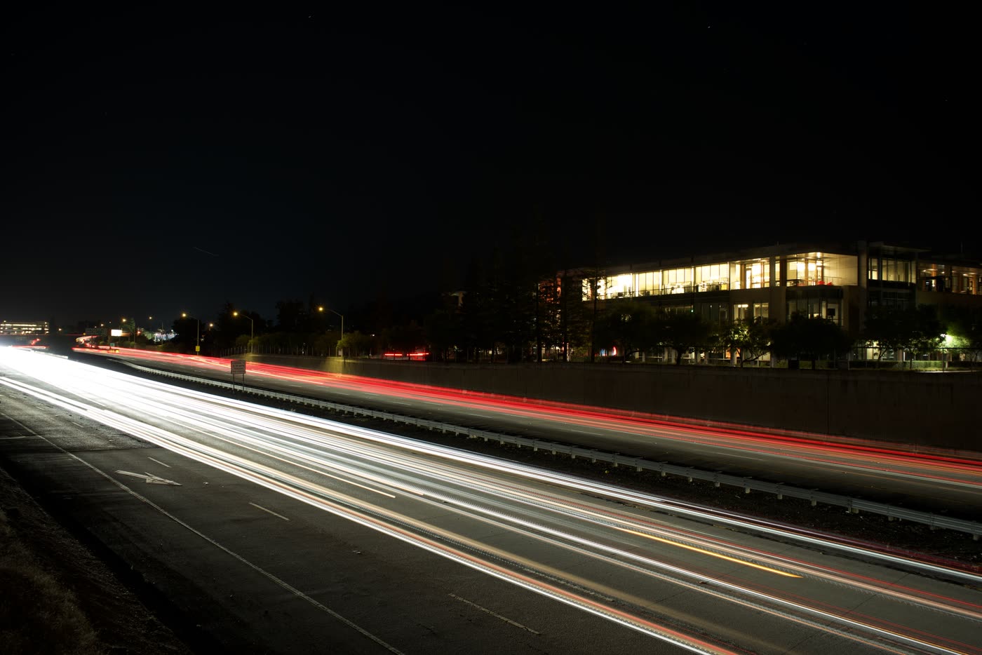Red and white car light trails streaking along a road at night