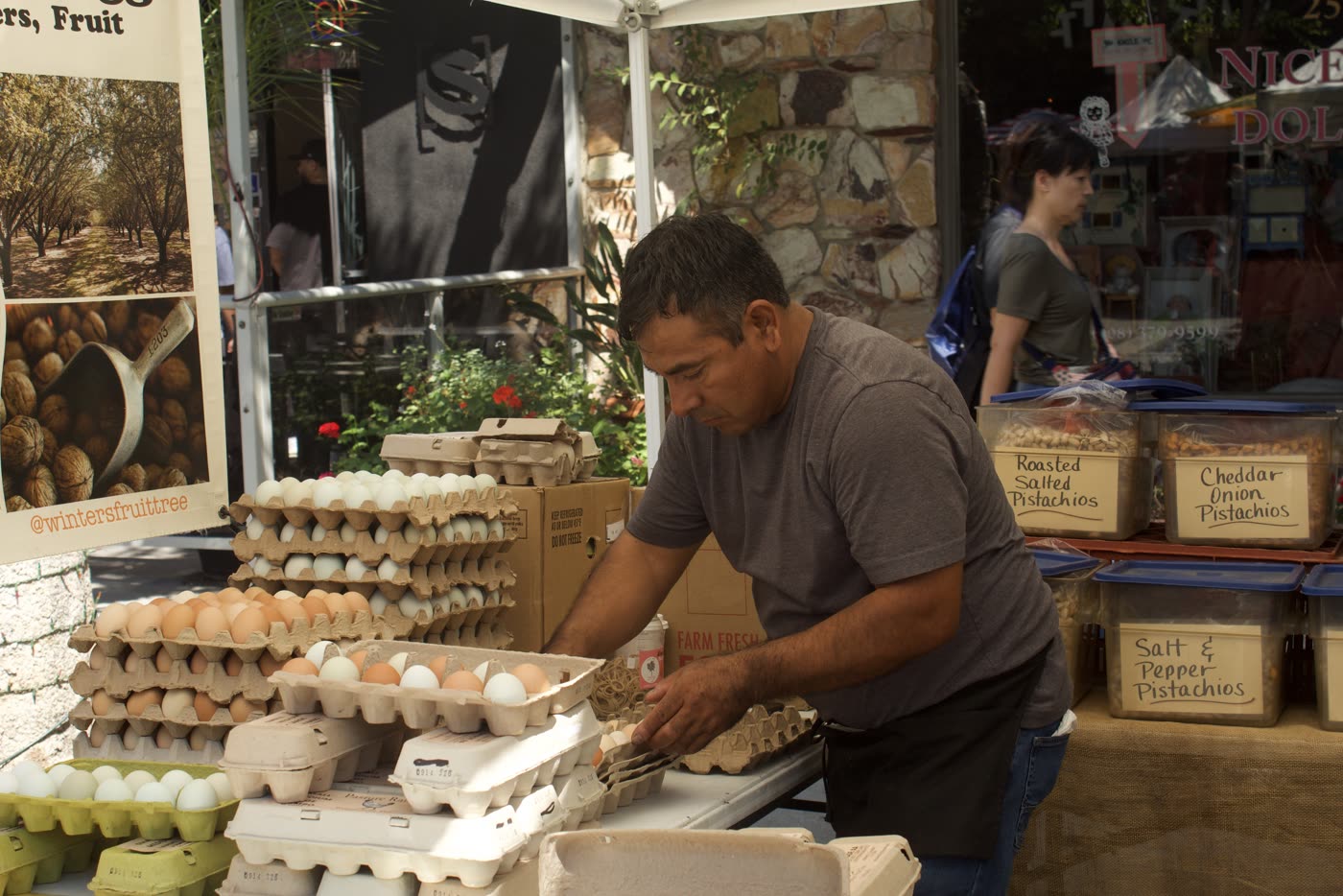 A vendor sorting cartons of eggs at an outdoor market stall