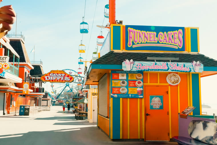 A brightly painted funnel cake stand on a seaside boardwalk