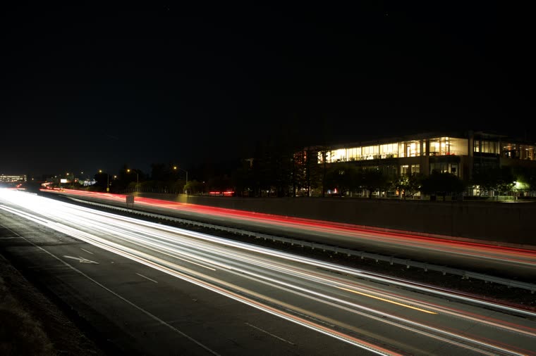 Red and white car light trails streaking along a road at night